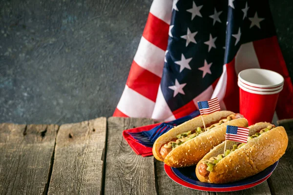 Día Nacional del Trabajo, Día de los Caídos, Día de la Bandera, 4 de julio - perros calientes con salsa de tomate y mostaza sobre fondo de madera —  Fotos de Stock