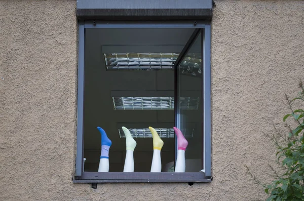 Gri duvar penceresinde renkli çoraplı manken ayaklı