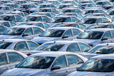 Güneşli bir günde bir araba fabrikasında dağıtım merkezine park edilmiş yeni arabaların sıraları. Açık havaya park etmek..