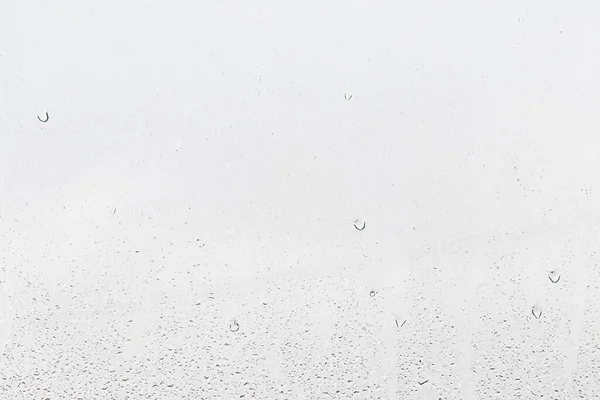 Rain drops on window glasses surface with gray sky background . Natural backdrop of raindrops. Abstract overlay for design. The concept of bad rainy weather.