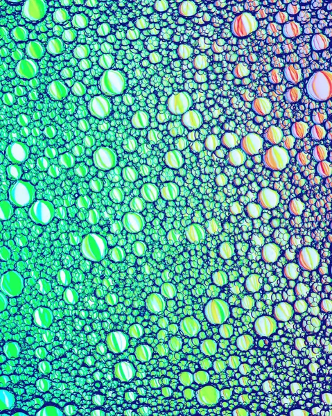 Colorful drops of oil on the water. Circles and ovals. Abstract bright background for design with reflection and refraction.