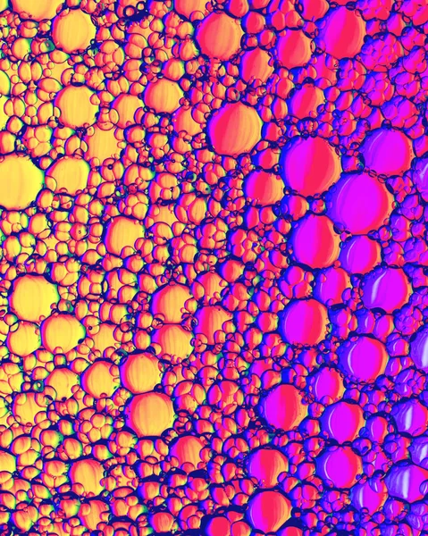 Colorful drops of oil on the water. Circles and ovals. Abstract bright backdrop for design with reflection and refraction.