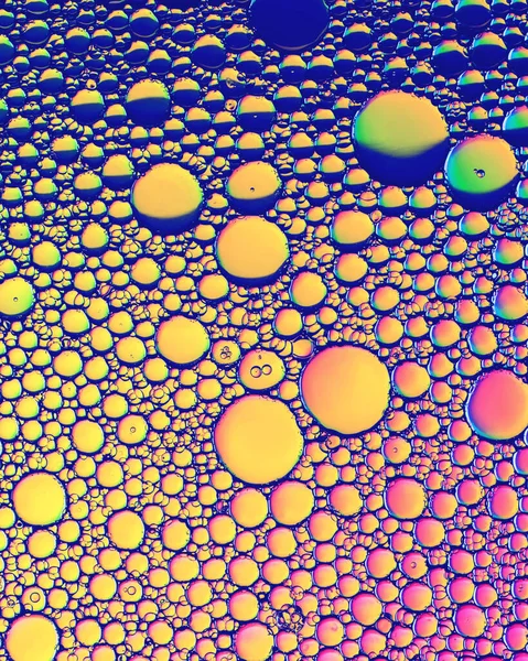 Colorful drops of oil on the water. Rainbow or spectrum colored circles, ovals. Abstract bright background for design.