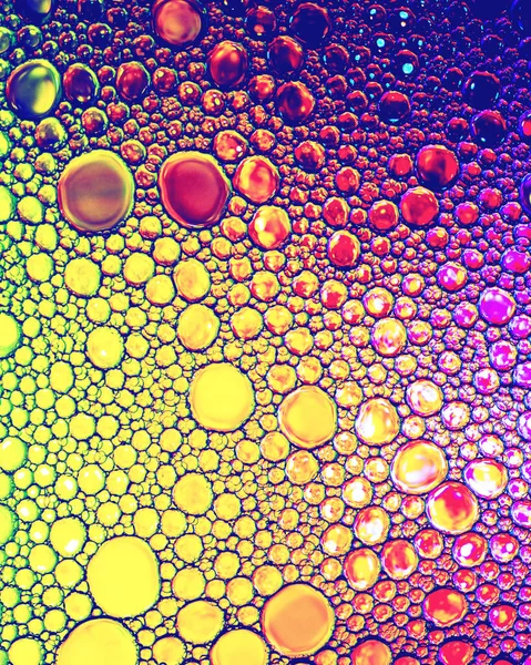 Colorful drops of oil on the water. Rainbow or spectrum colored circles, ovals. Abstract bright background for design.