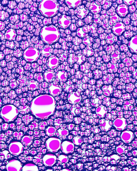 Top view on colorful drops of oil on the water. Circles and ovals. Abstract pink background for design with reflected refracted shapes.