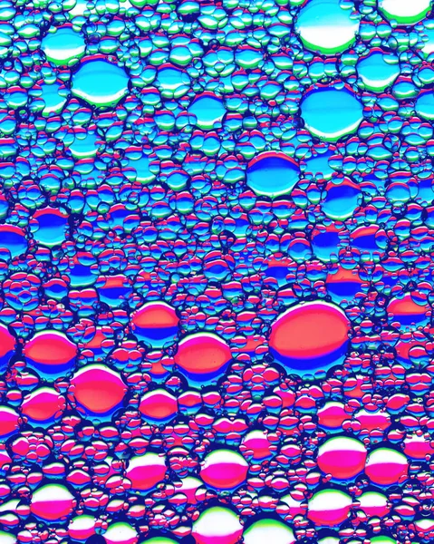 Colorful drops of oil on the water. Circles and ovals. Abstract bright background for design with reflection and refraction.