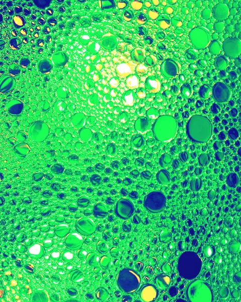 Colorful drops of oil on the water. Green colored circles, ovals. Abstract bright background for design.