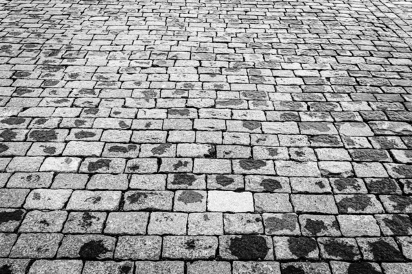 Top view on paving wet stone road after rain. Old pavement of granite texture. Street cobblestone sidewalk. Abstract background for design.