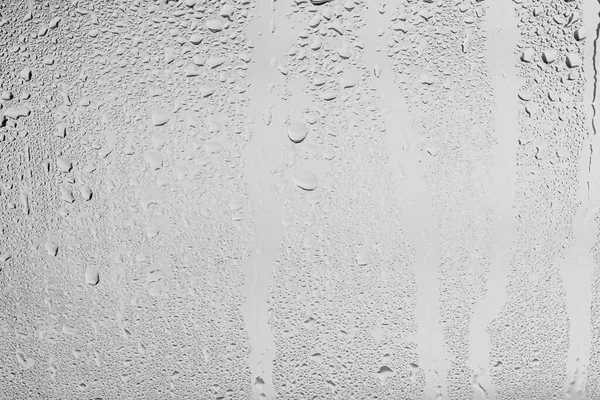 Rain drops on window glasses surface with gray sky background . Natural backdrop of raindrops. Abstract overlay for design. The concept of bad rainy weather.