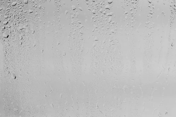 Rain drops on window glasses surface with gray sky background . Natural backdrop of raindrops. Abstract overlay for design. The concept of bad rainy weather.