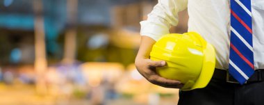 Erkek mühendis el Sarı kask açık havada tutan