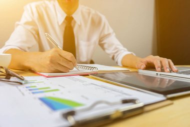 Office belgeleri üstünde okul sırası ve laptop ile çalışan adam 