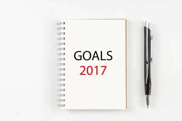 Top view of notebook with goals 2017 text and pen on white background