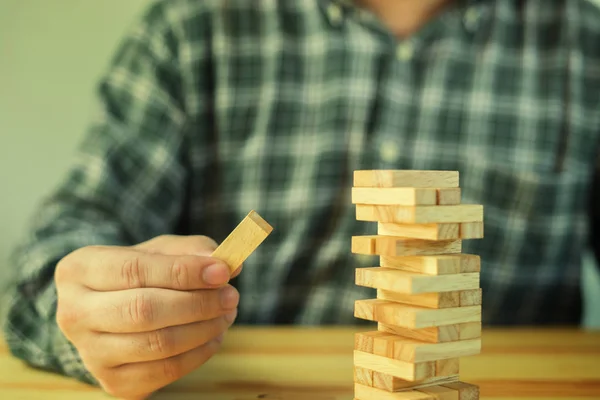 man playing wood blocks tower game jenga in office