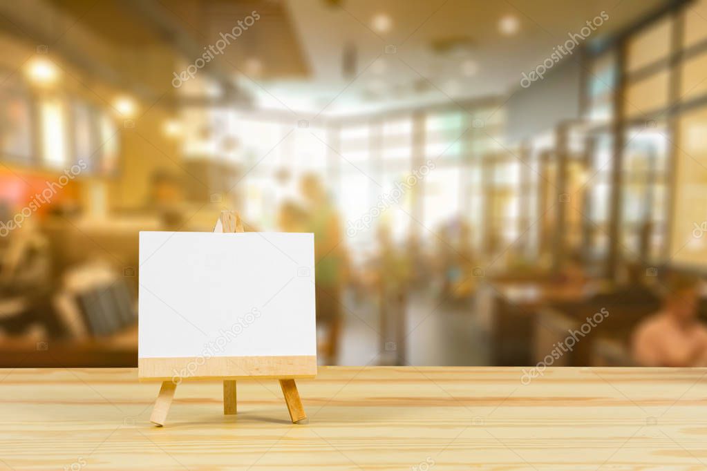 blank white canvas on easel with copy space on wooden table in selective focus 