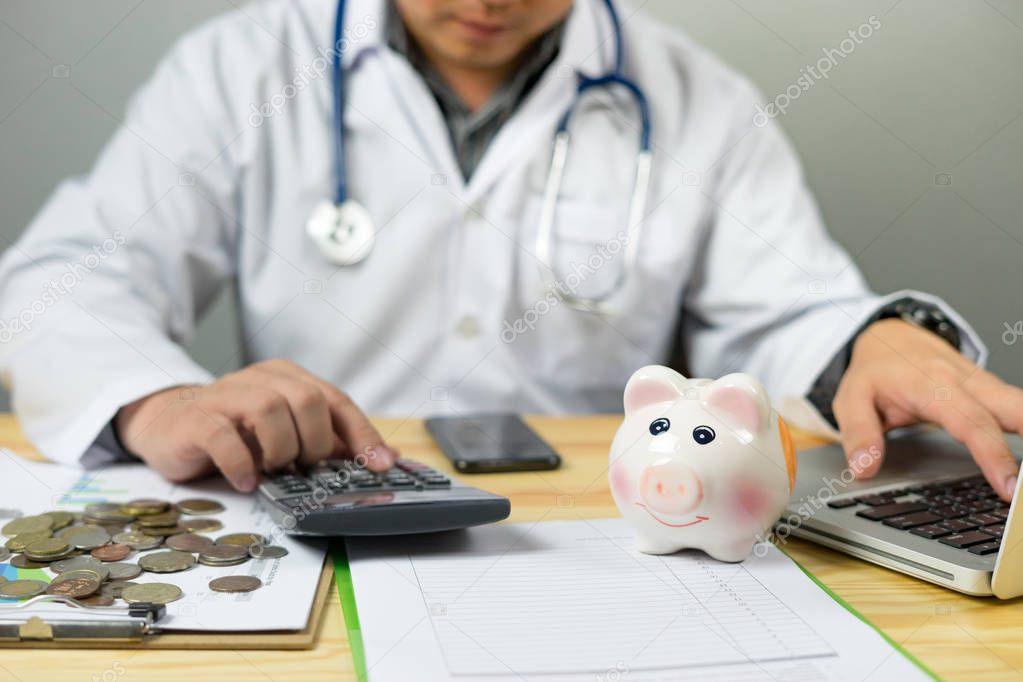 Doctor holding piggy bank and counting coins with calculator