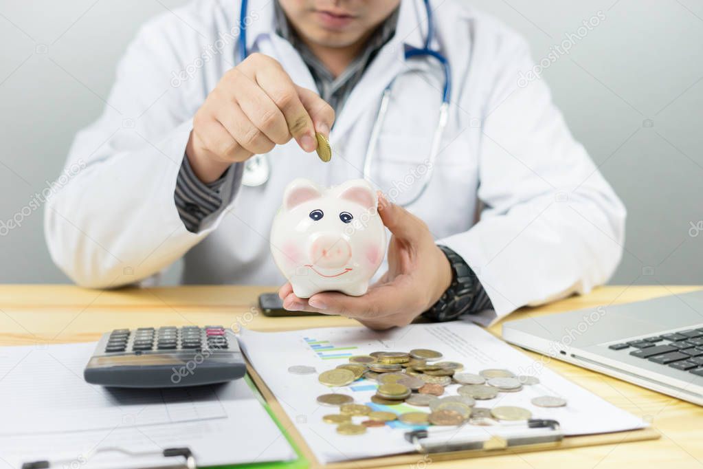Doctor holding piggy bank and counting coins with calculator