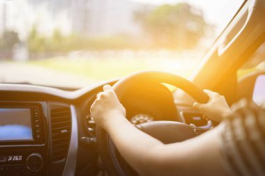 Arkadan aydınlatmalı arabada direksiyon simidi üzerinde eller