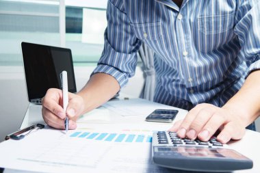 İş adamı, hesap makinesi ve iş grafiği ile ofis masasında çalışıyor.