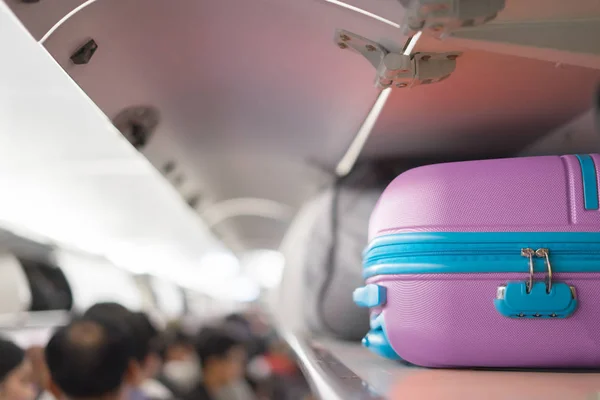 luggage on top shelf on airplane with people on board
