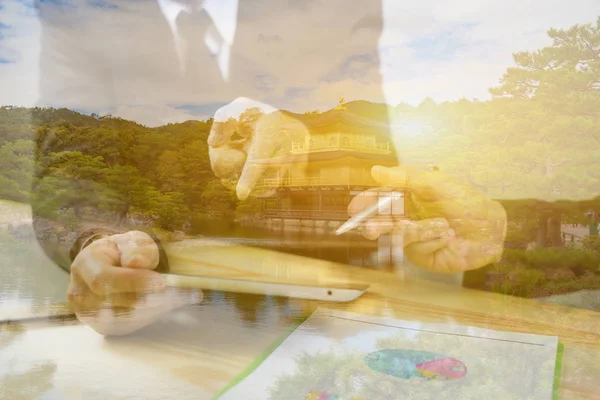 Double exposure of businessmen learning diagrams at meeting in office and building in forest