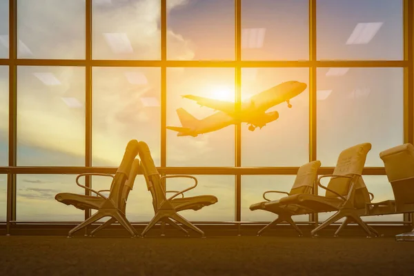 passenger seats in departure lounge and plane at background in airport