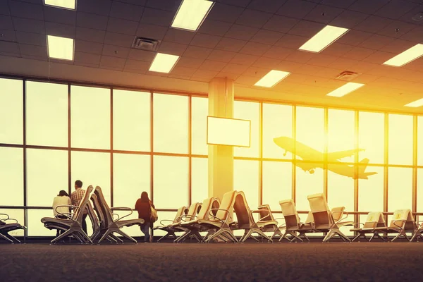 passenger seats in departure lounge with people at background in airport