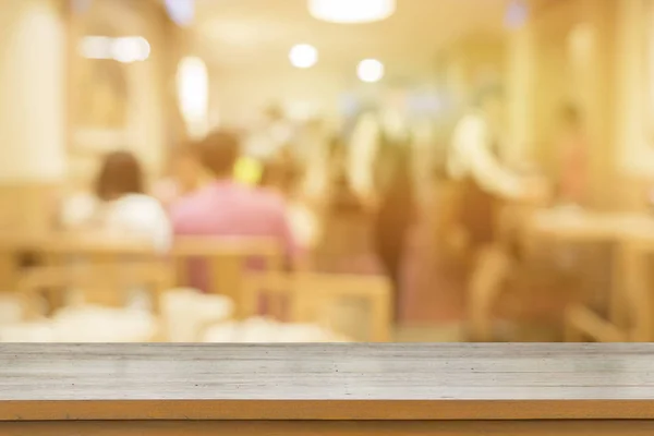 Empty brown wooden table at restaurant with blurred people at background with bokeh lights