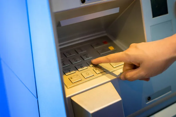 male hand pressing password for withdrawing money from indoor bank