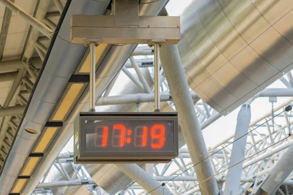 Digital LED clock with red lights hanging on ceiling at airport