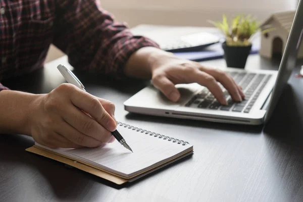 Male Manager Writing Empty Notebook Using Laptop Stock Photo