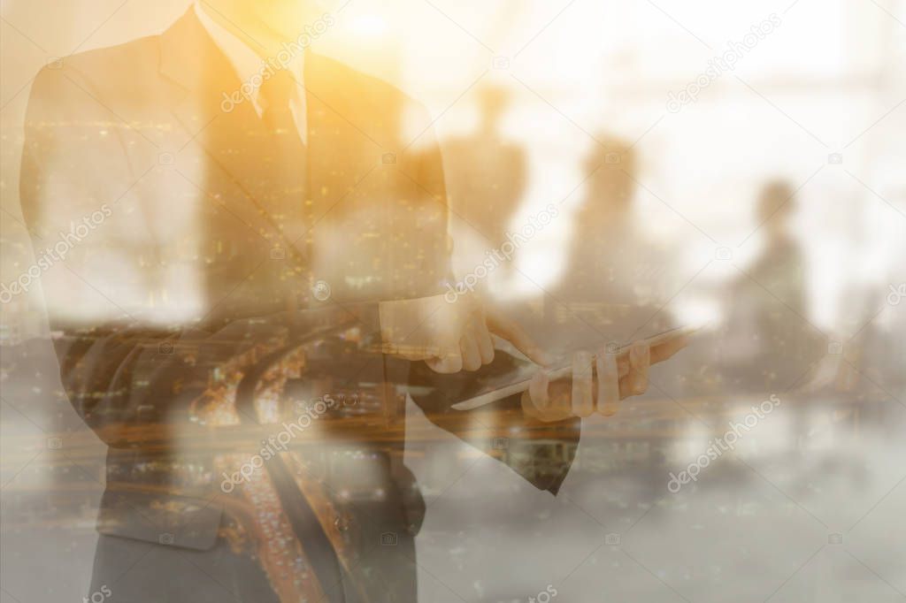 Double exposure of young man using digital tablet in office and cityscape