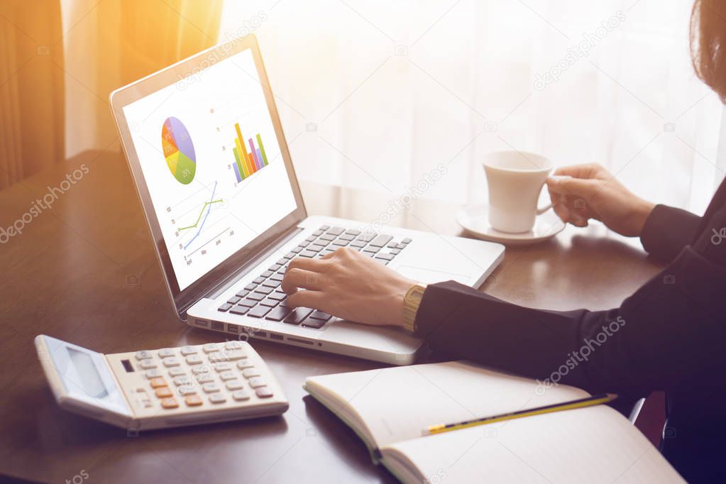 woman checking diagrams on laptop and drinking coffee