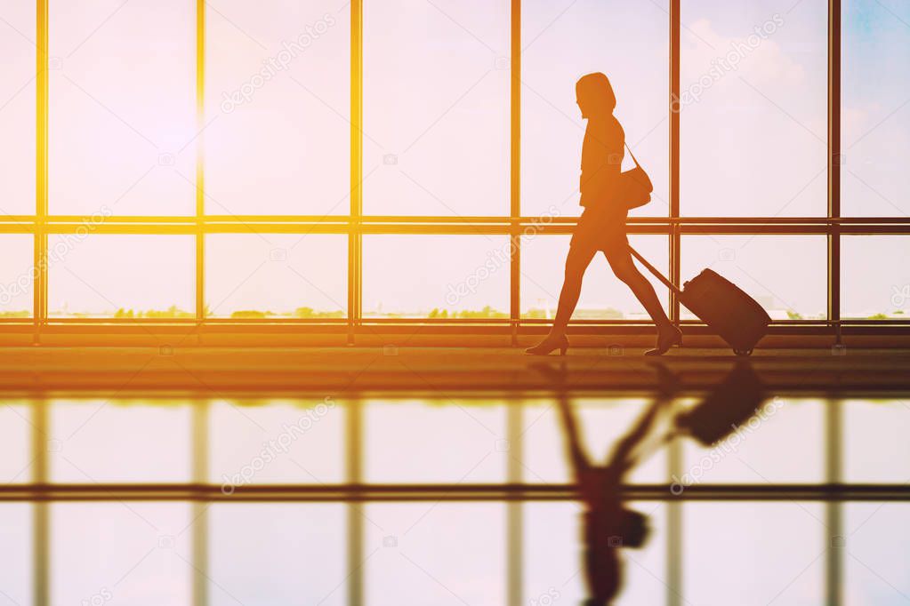female tourist walking at airport with luggage at sunset