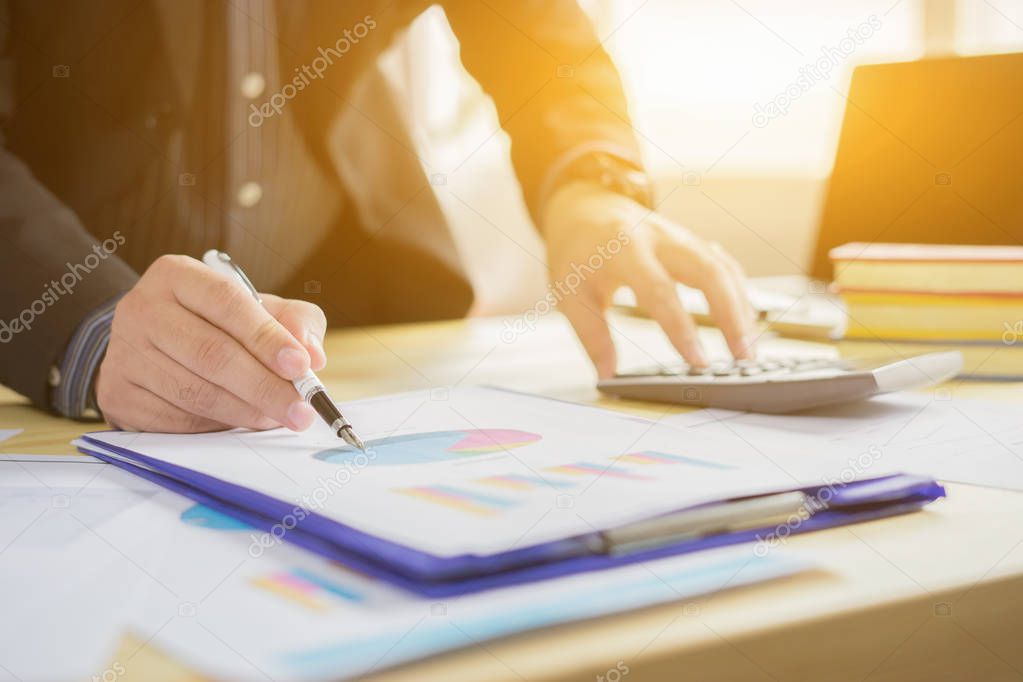 young business studying diagram and working with calculator in office