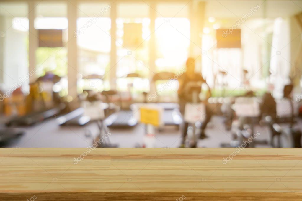 Empty brown wooden table top on blurred background of fitness gym