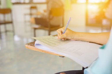 Sınavda ya da derste kalemle defter kağıdına yazan öğrenci