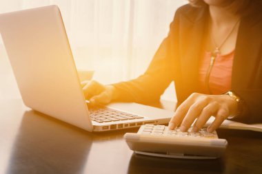 Masa üstünde laptop tarafından hesap makinesini kullanarak iş kadını