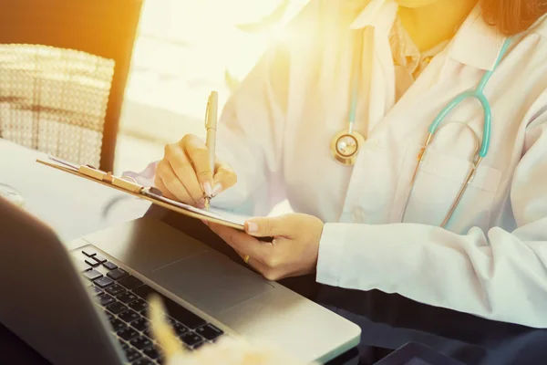 Doctora Escribiendo Con Pluma Portapapeles Por Ordenador Portátil Escritorio — Foto de Stock