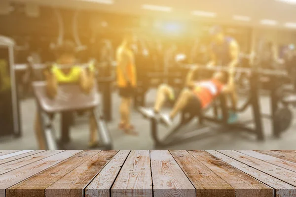 Empty brown wooden tabletop on blurred background of fitness gym