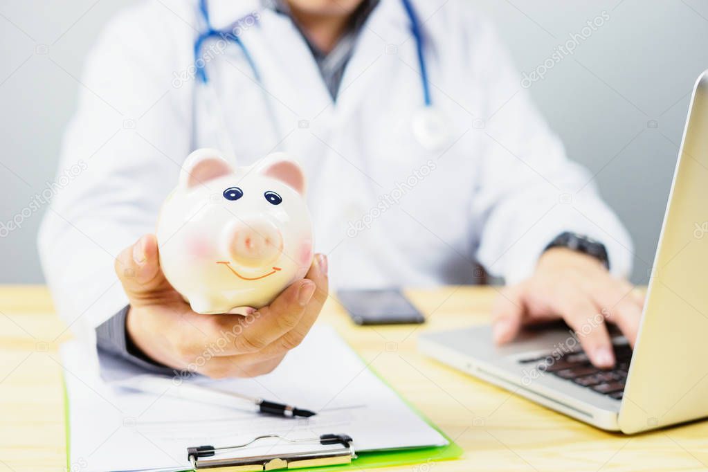 cropped image of doctor holding piggy bank at hospital