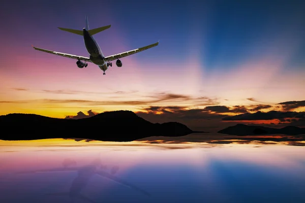 Airplane flying over tropical sea at beautiful light sunset or sunrise with reflex in the water at phuket thailand scenery background