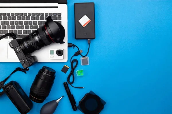 Digital camera with lenses and equipment of the professional photographer on blue paper background