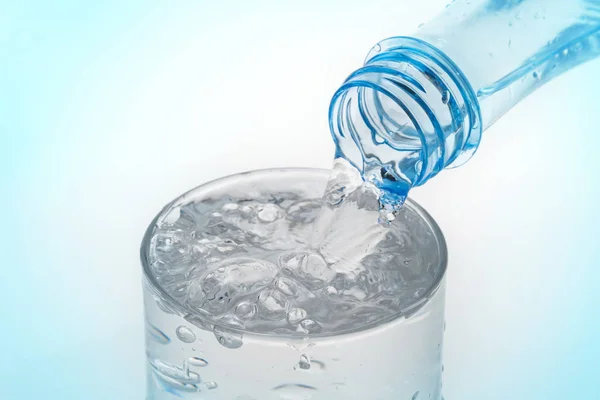 Наливаємо Воду Пляшки Склянку Синьому Фоні — стокове фото