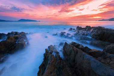 Uzun pozlama görüntü günbatımı manzara arka planda rock ile dramatik gökyüzü ve dalga deniz manzarası