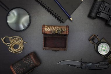 Pusula, kağıt, kalem, defter, cep saati, ip, siyah ahşap zemin üzerine büyüteç ile çakı.