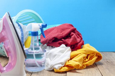 Renkli elbise ve ütüler, ahşap tahta, mavi renk arka plan üzerine püskürtülen ilaç şişe yığını.