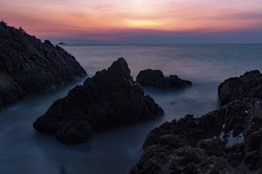 Dramatik gökyüzünün günbatımı manzaralı kayalıklı uzun pozlama görüntüsü.. 