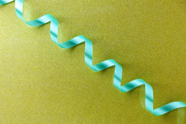 Křivka zelená stuha na zlaté papírové pozadí — Stock fotografie