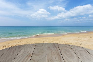 Tropikal kumlu plaj ve mavi okyanus, mavi gökyüzü ile ahşap zemin 